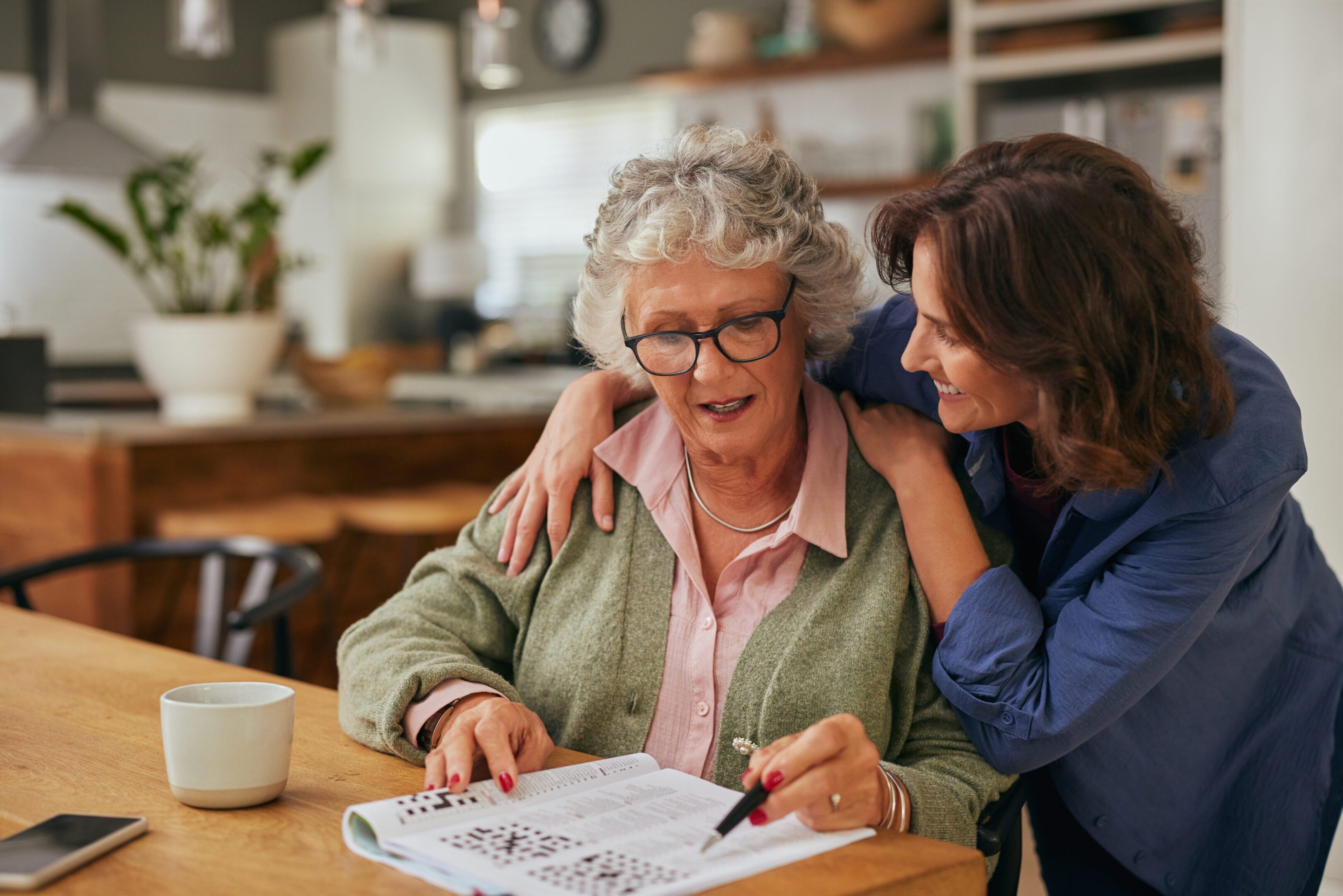 Elderly woman solving puzzle with younger woman.